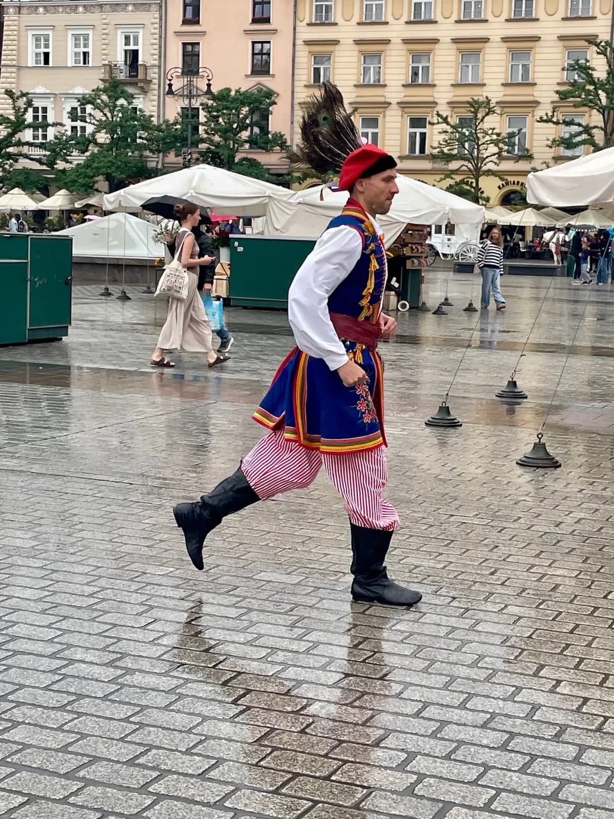 Un danseur en costume traditionnel sur la place du Marché mouillée par la pluie, Cracovie