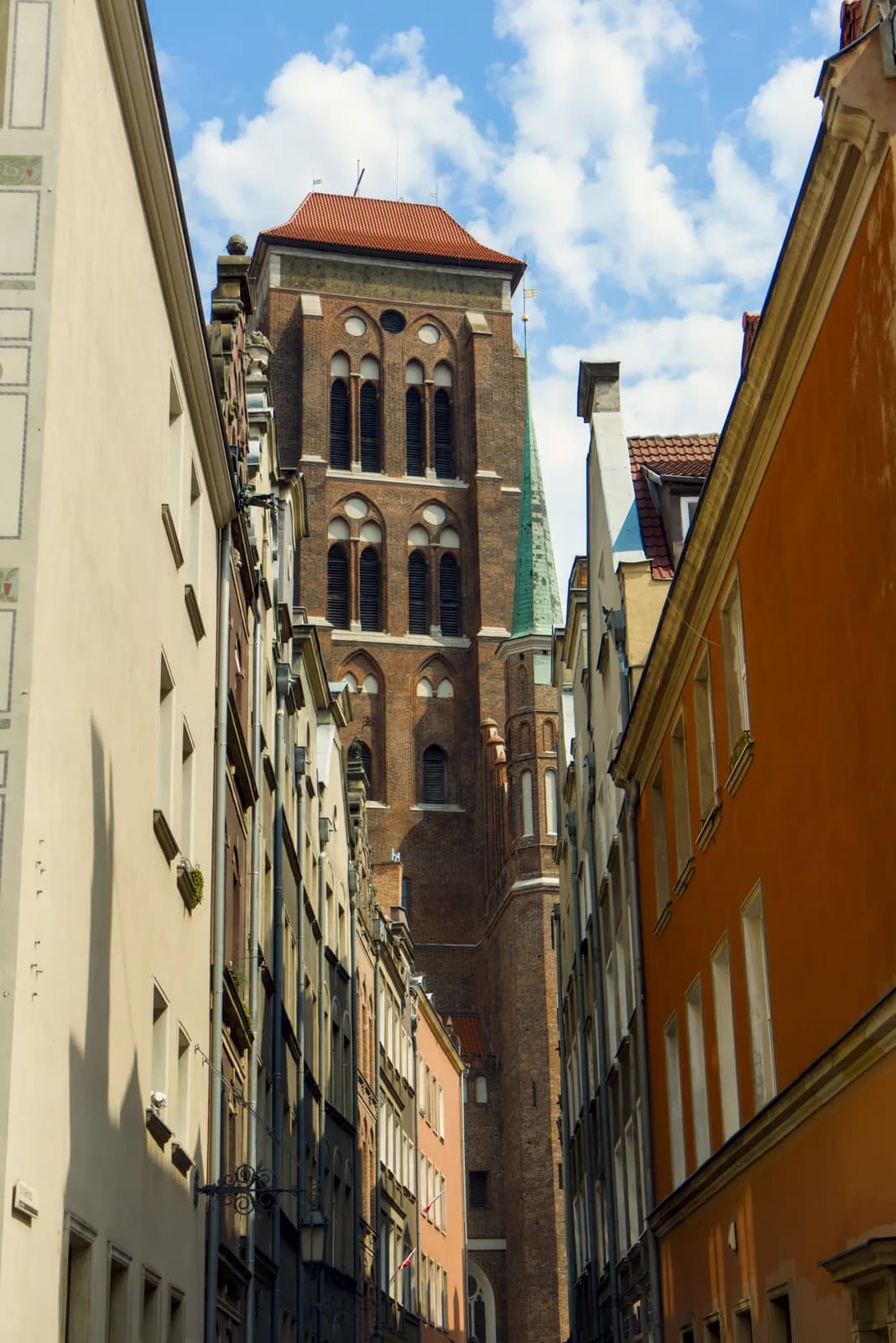 La tour de la basilique Sainte-Marie encadrée par les façades d'une ruelle du centre historique de Gdańsk