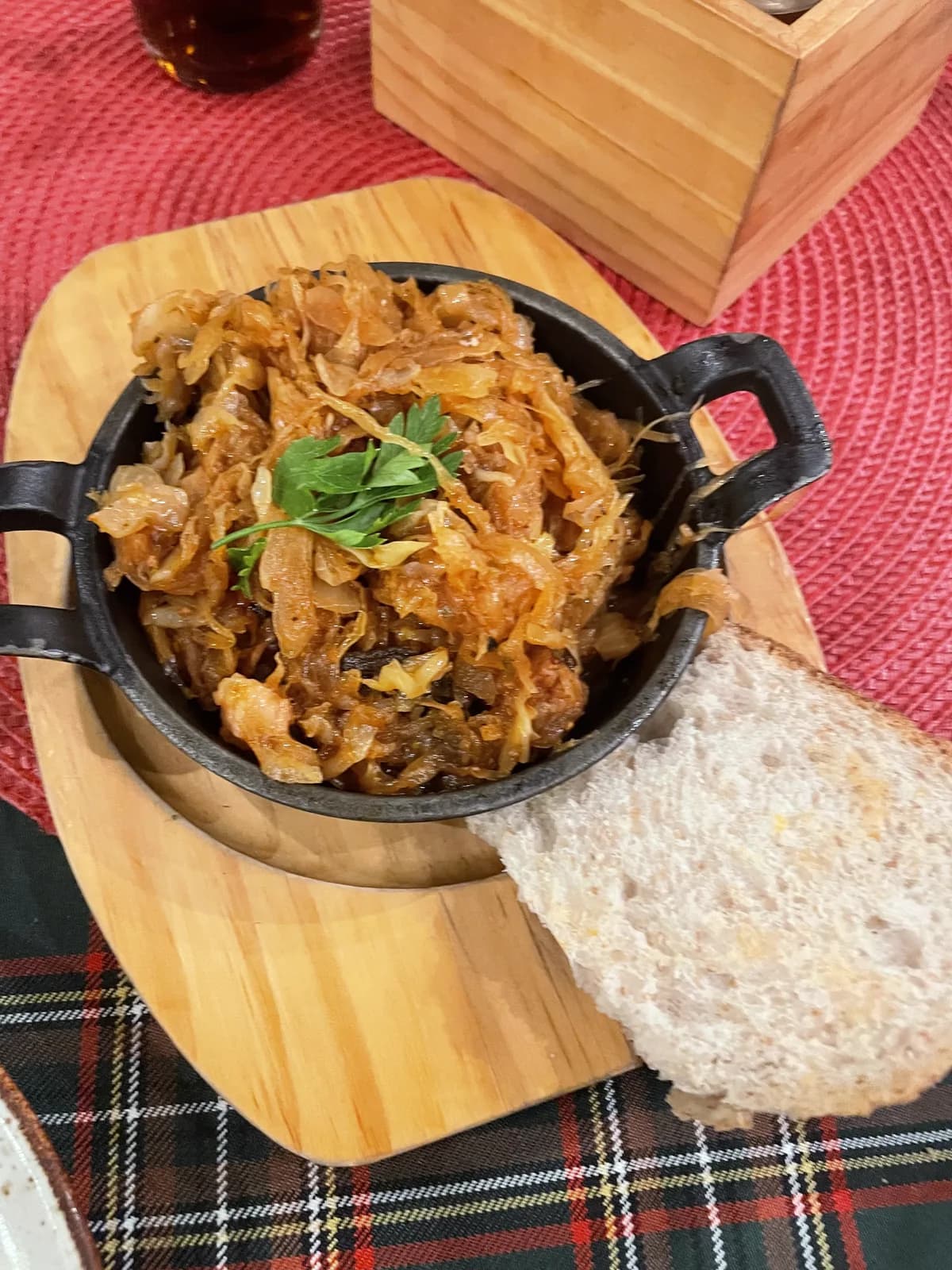 Bigos servi en cocotte en fonte avec une tranche de pain